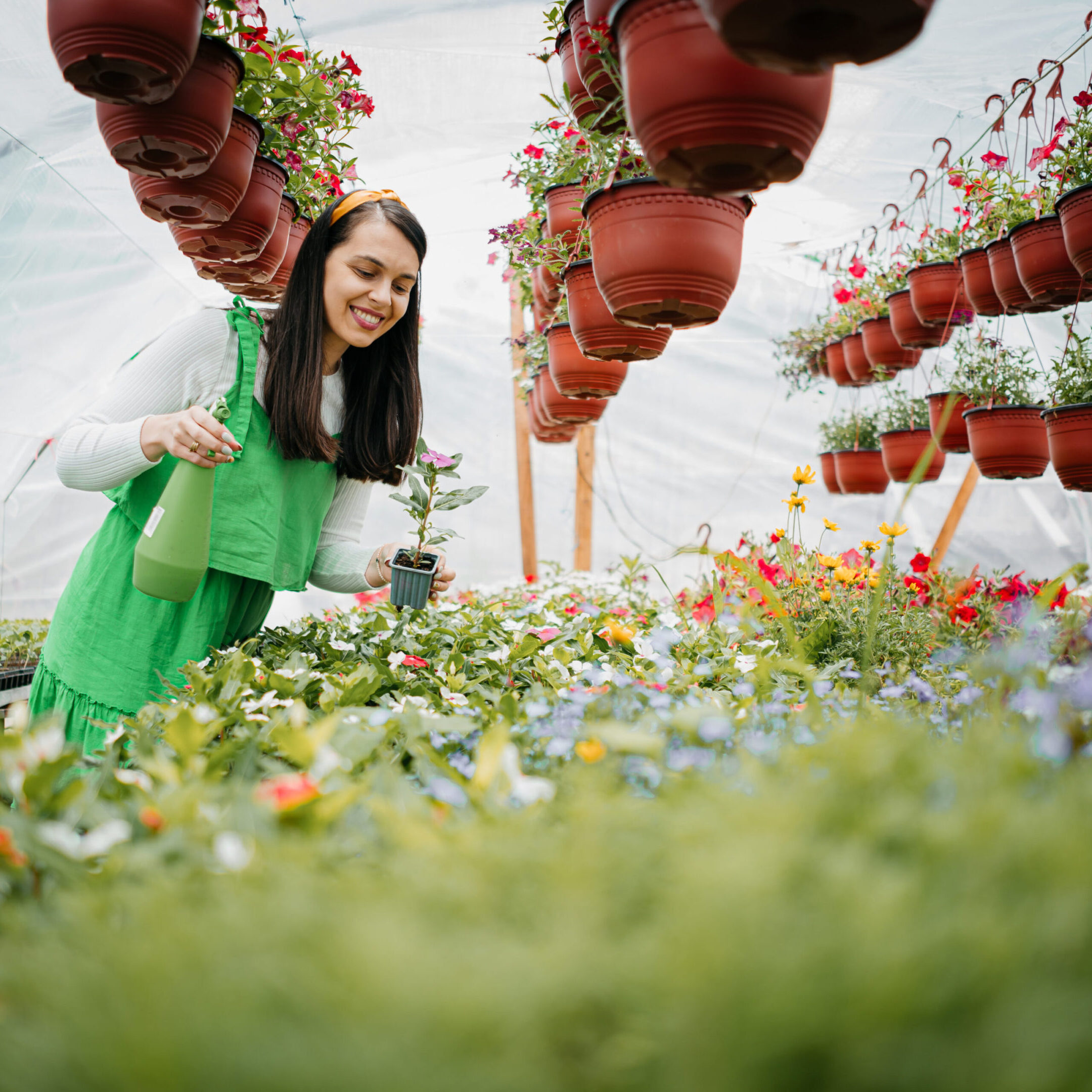 A woman in green admiring flowers in a vibrant garden.
